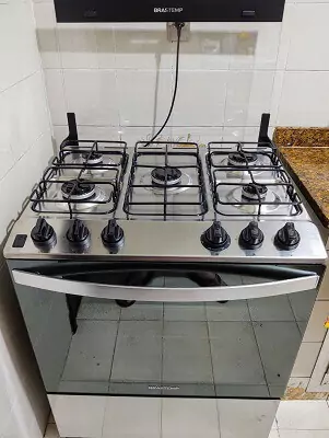 Brastemp BFS5N em close frontal, com o vidro da mesa levantado e sem panelas nas bocas.