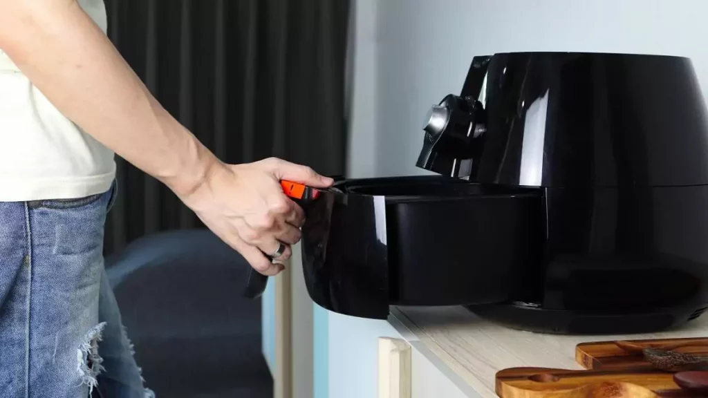 Abertura do post sobre como usar air fryer: Homem abrindo fritadeira preta