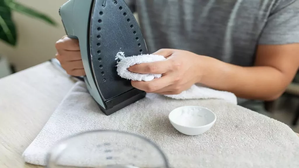 Abertura do post sobre como limpar ferro a vapor: Mulher limpando base de ferro