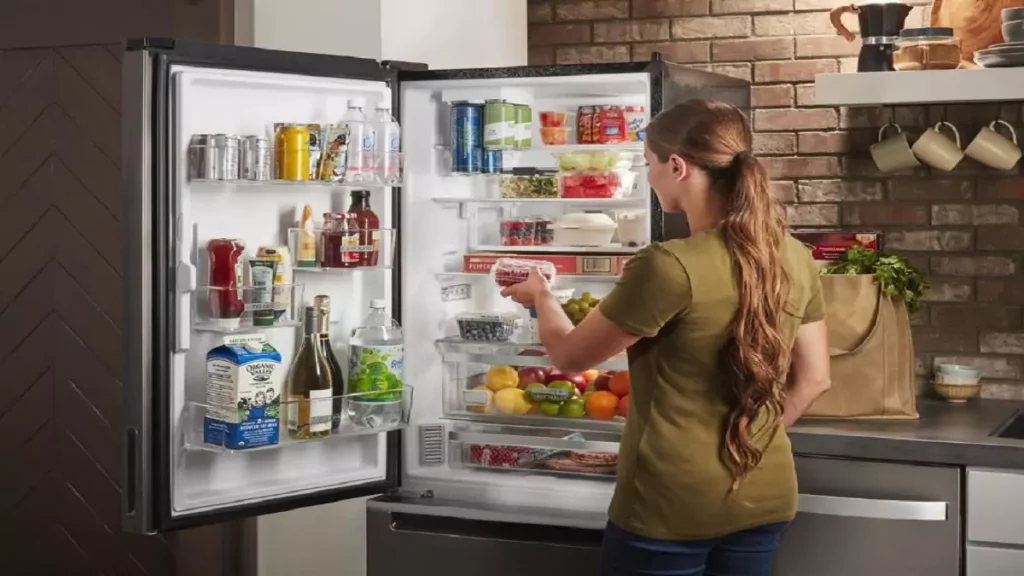 Mulher pegando alimentos em geladeira inverse